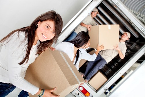 Movers carrying furniture through a Belmont flat corridor